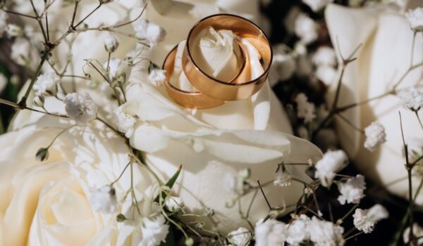 Golden wedding rings on the white rose from the wedding bouquet