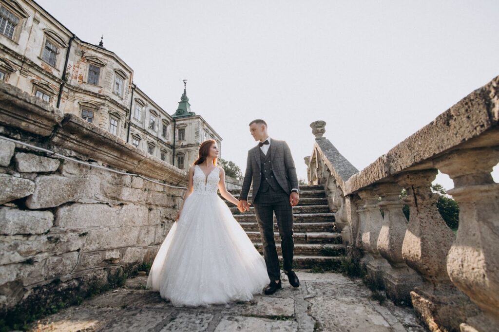 Beautiful couple posing on their wedding day near mansion