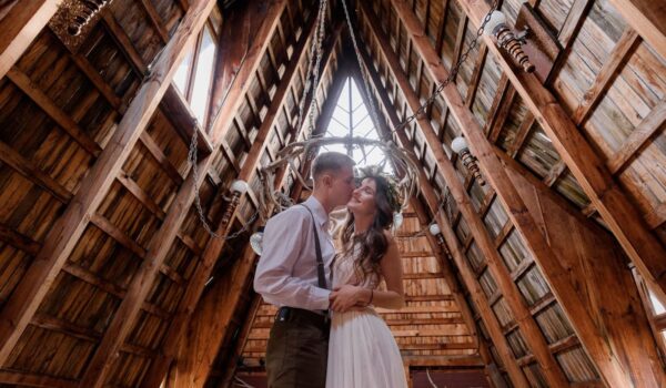 Groom and bride kissing in wooden building