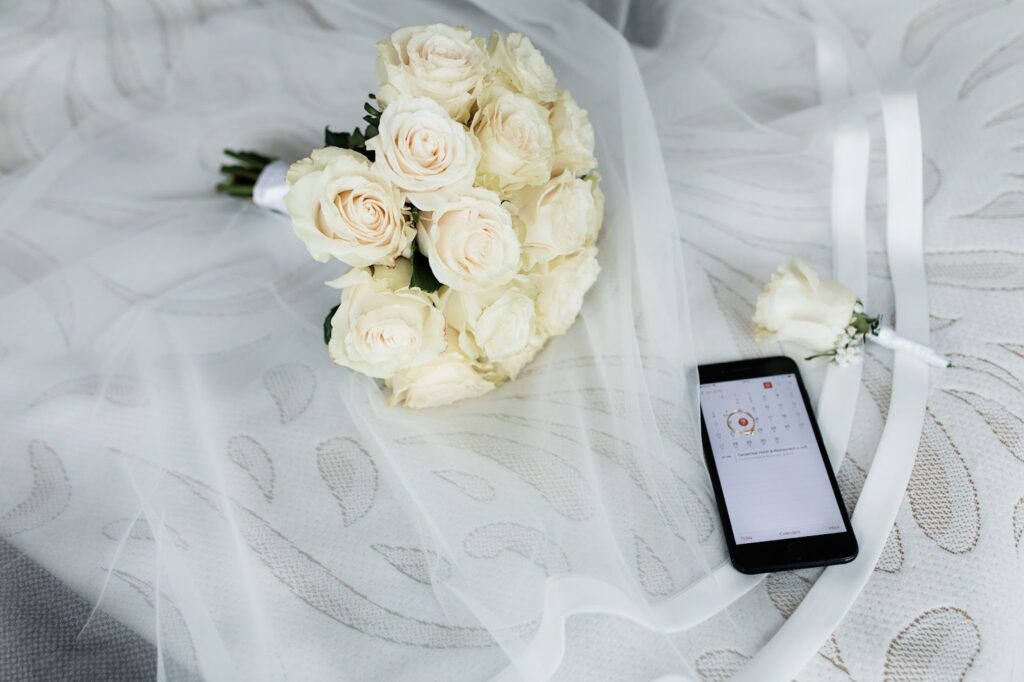 Top view of smartphone with opened calendar and wedding bouquet of white roses