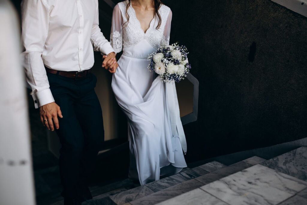 Groom holds bride's hand while they go upstairs