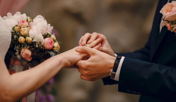 Groom putting ring on bride's finger